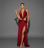 Woman wearing a red evening gown with a plunging neckline and high slit on a gray background