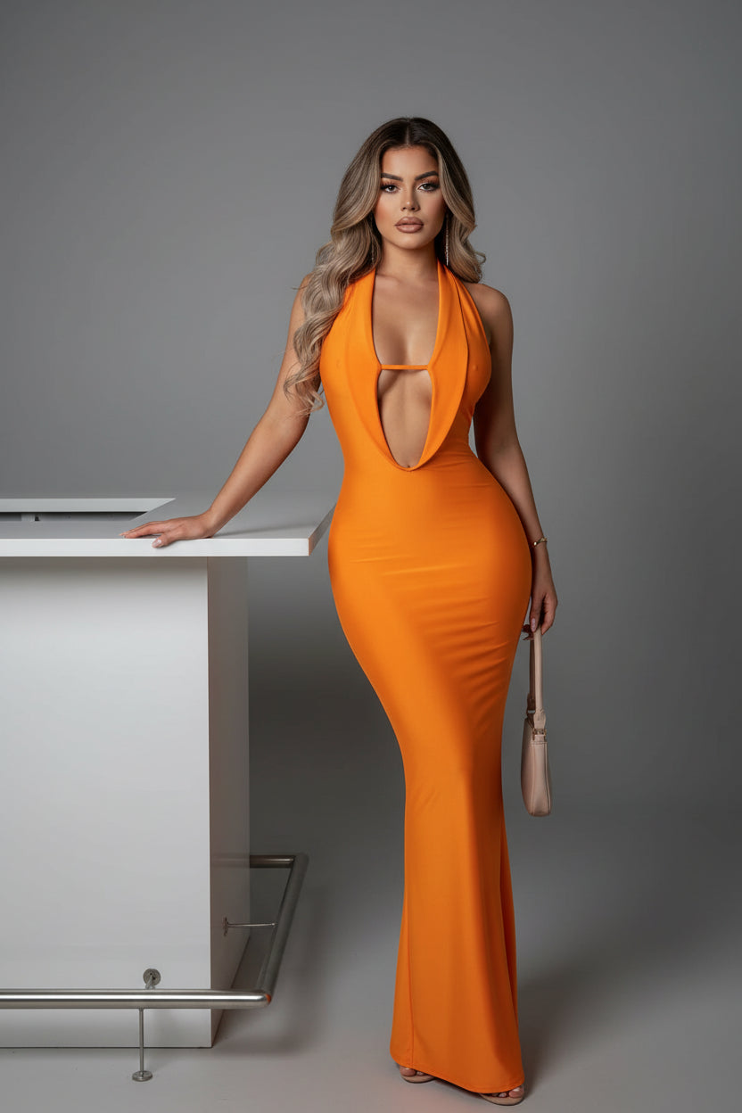 Woman wearing an orange evening gown with a plunging neckline, holding a handbag against a plain background.