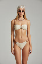 Beige bikini set with brown straps on a textured surface